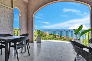 Uma varanda com vista para o mar, equipada com cadeiras de vime e uma mesa.