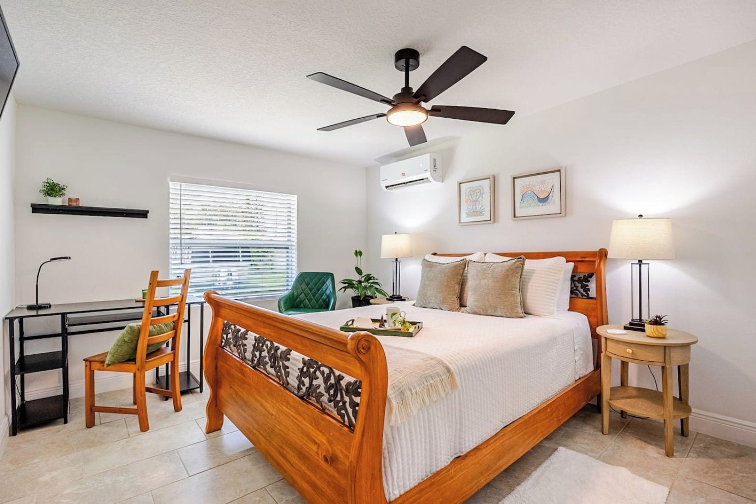 A bedroom with a bed, a desk, a chair, a ceiling fan, and a window with blinds.