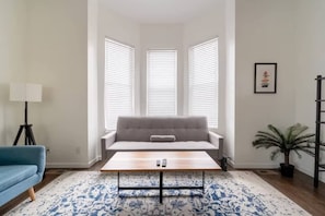 Ein Wohnzimmer mit einer Couch, einem Couchtisch, einer Lampe und einem Blumentopf.