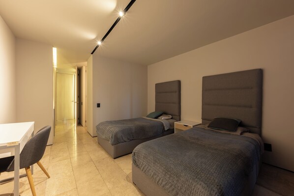 Une chambre d’hôtel moderne équipée de deux lits simples, d’un bureau et d’une chaise.