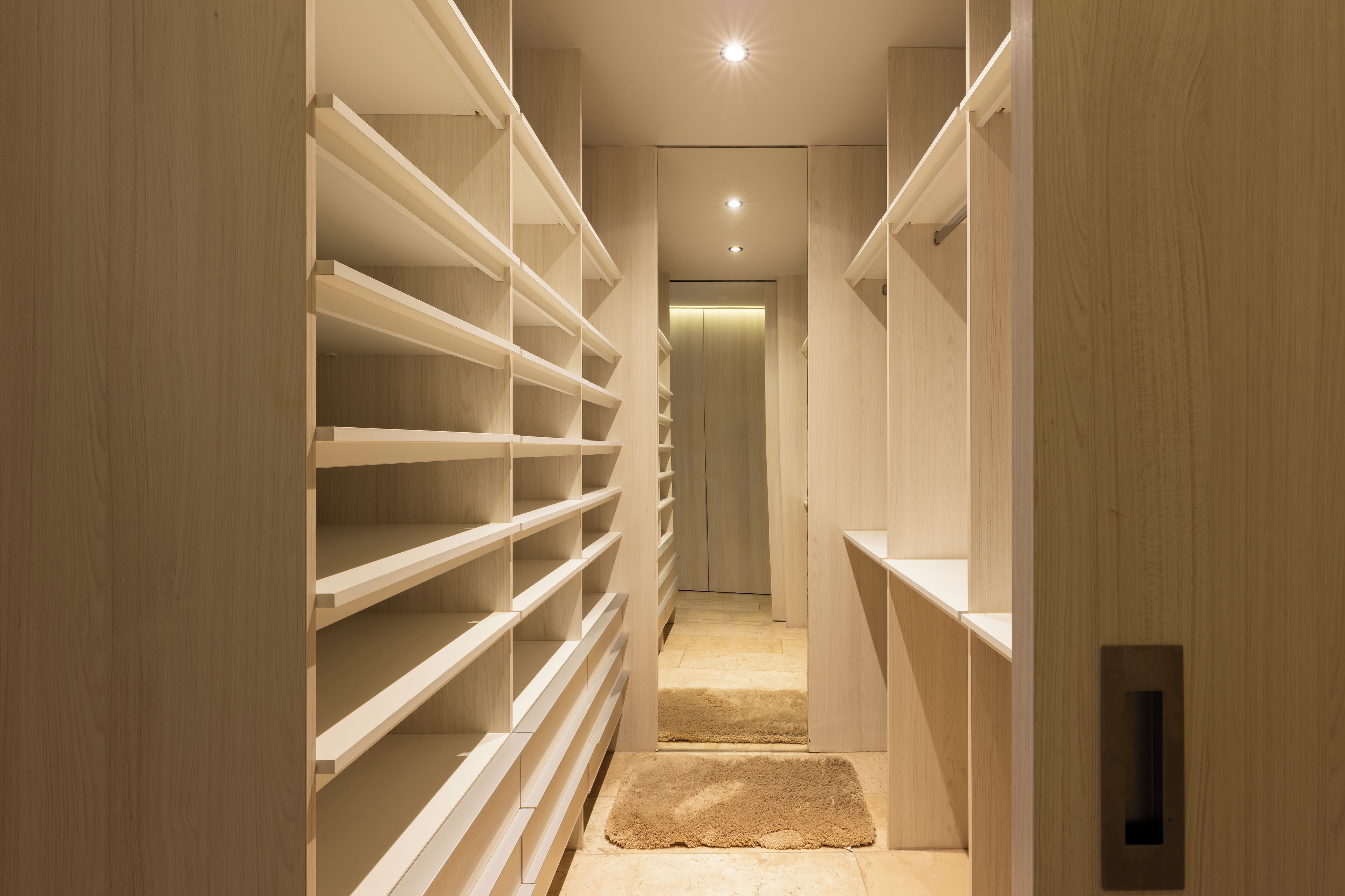 Spacious walk-in closet with custom shelving and warm modern design