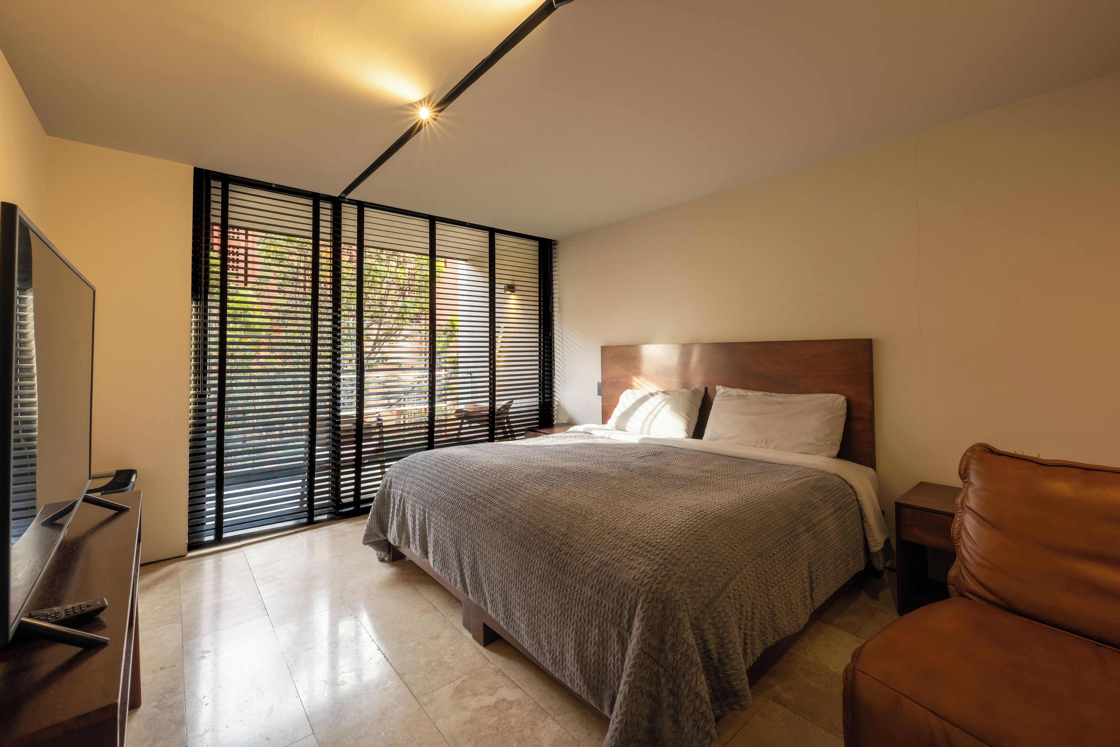A modern bedroom with a large bed, a TV, and a desk.