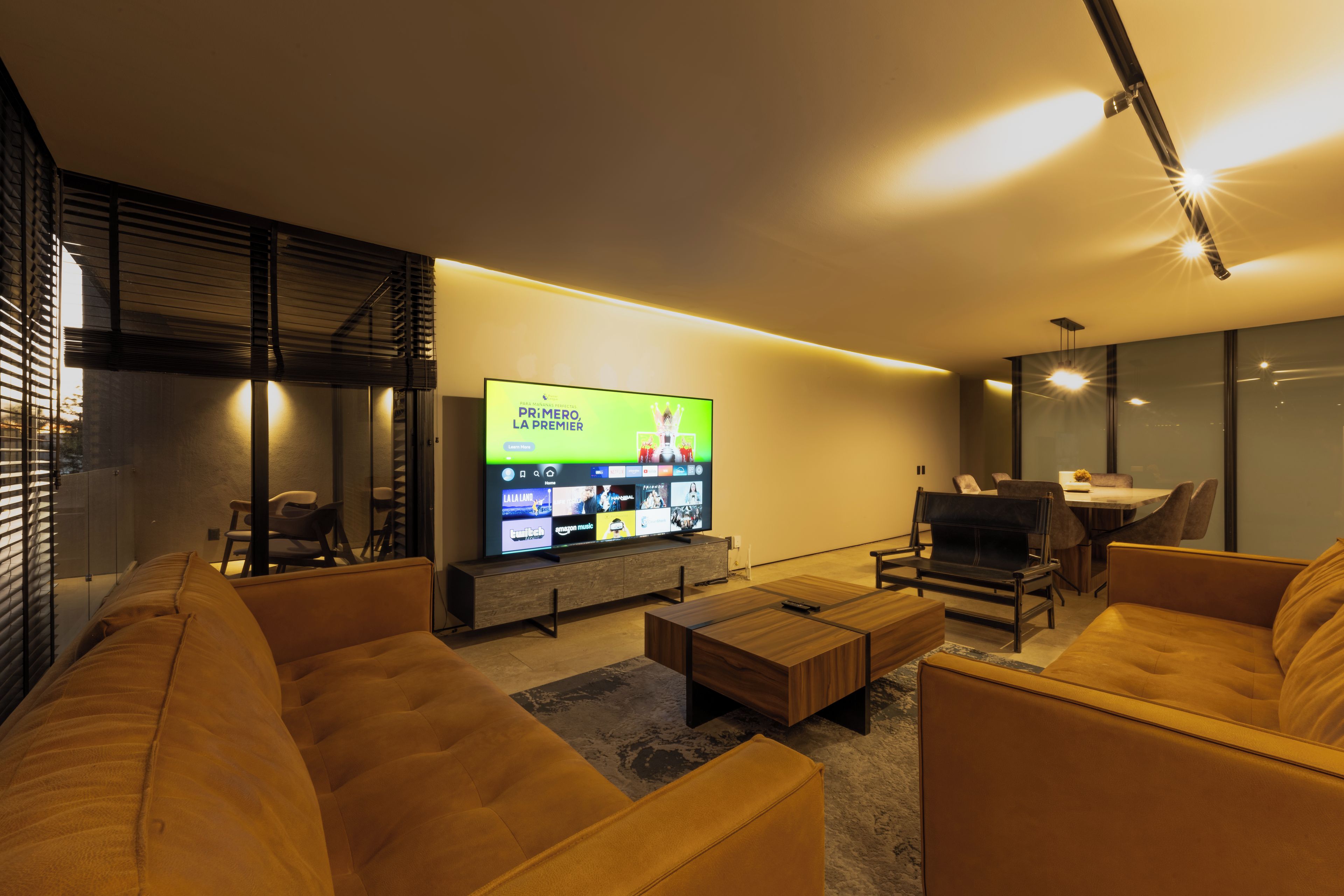 A modern living room with a flat-screen TV, comfortable seating, and a dining area.