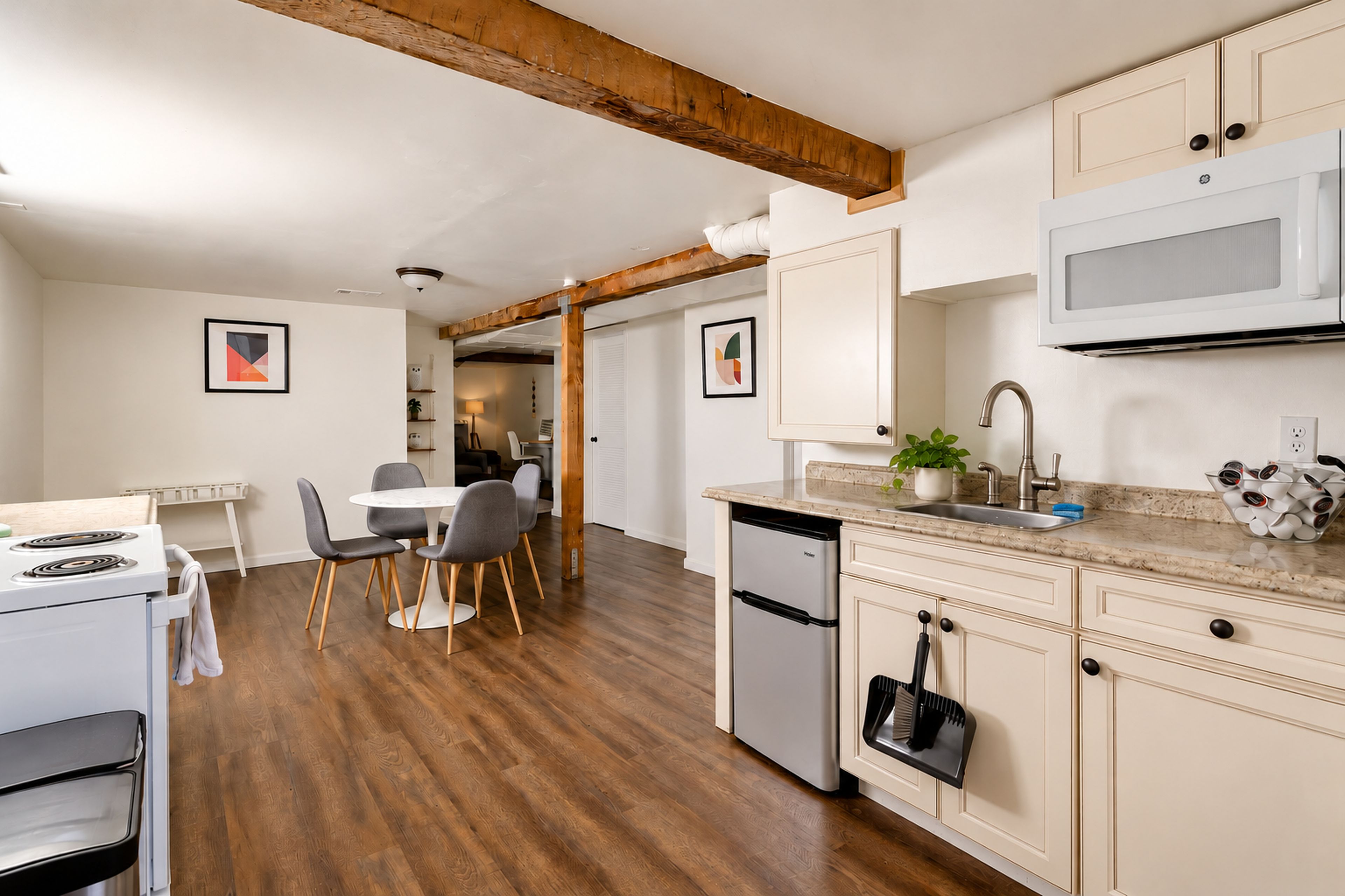 Una cocina moderna con suelo de madera, un comedor con mesa y sillas, y un microondas empotrado.