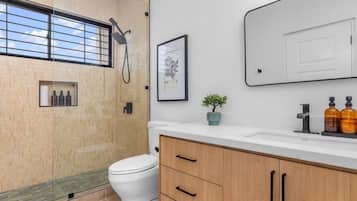 Une salle de bain moderne équipée de toilettes, d’une douche et d’un meuble-lavabo.