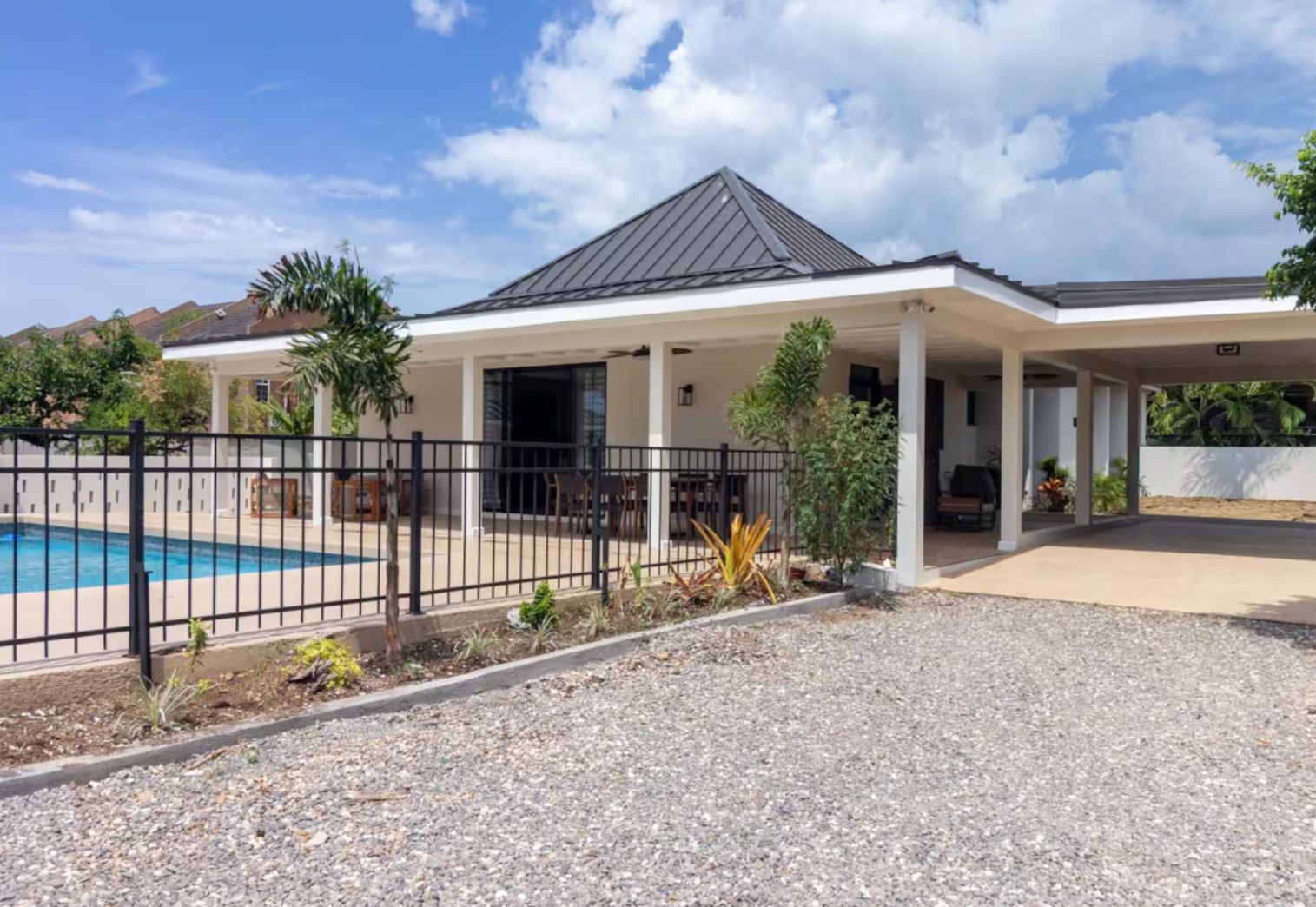 A residential property with a swimming pool, covered patio, and a fenced garden area.