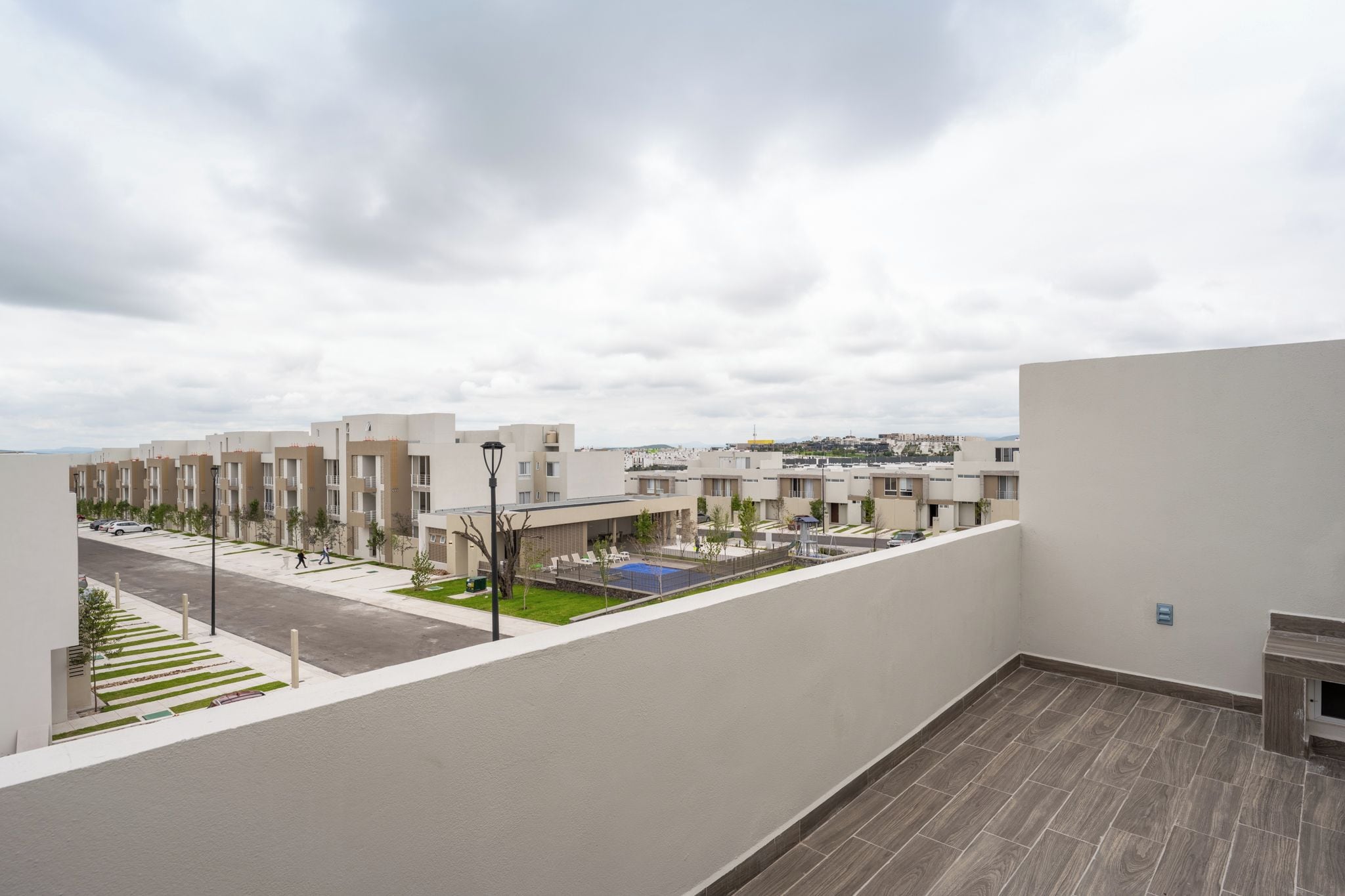 A residential area with modern buildings, a swimming pool, and a street.