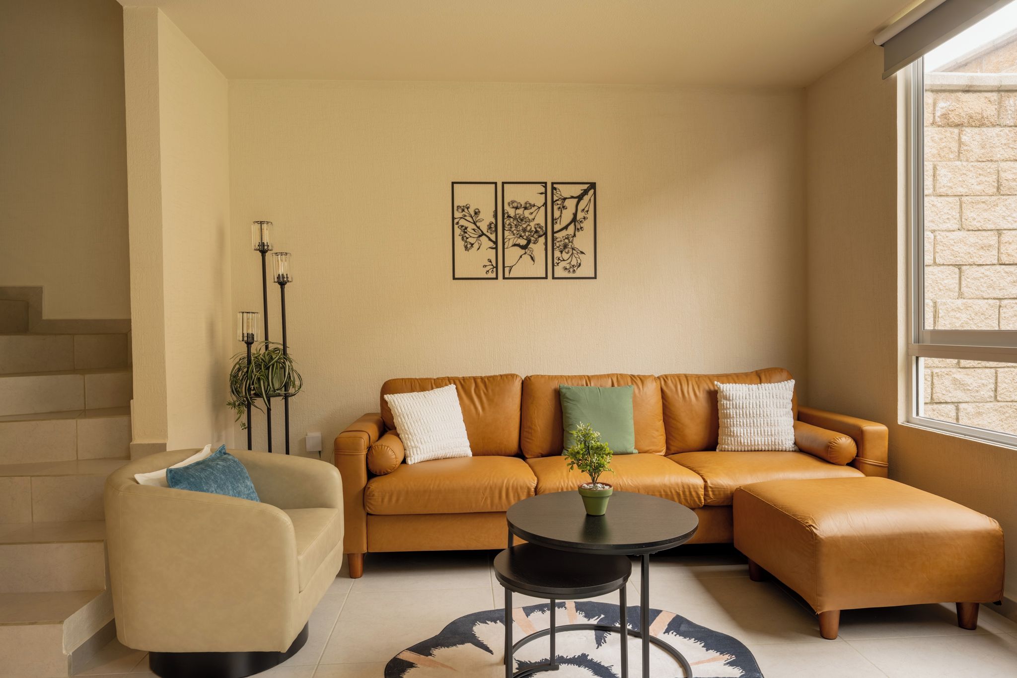 Un salon avec un canapé, un fauteuil et une table basse. On peut voir une plante en pot sur la table basse.