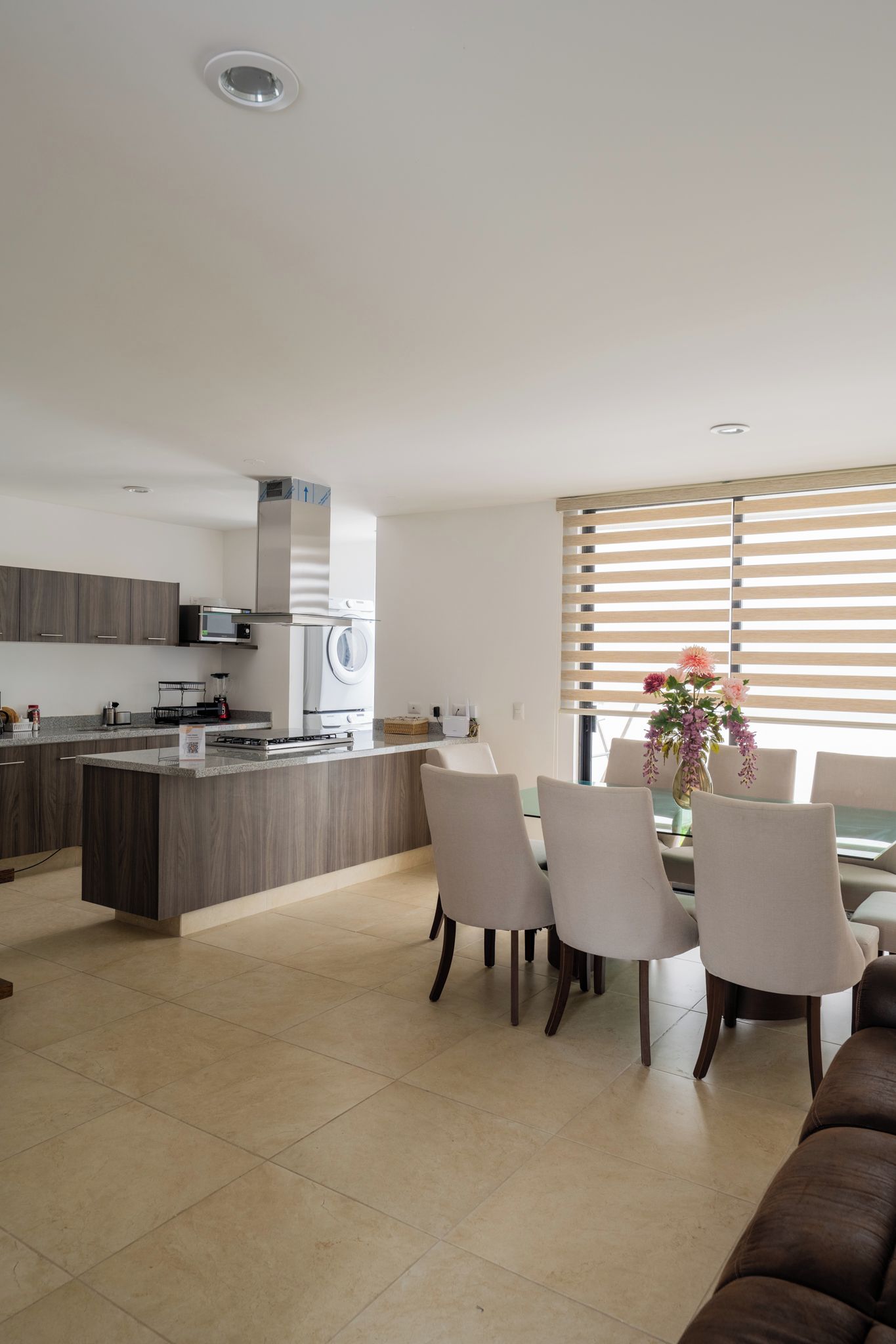 Une cuisine moderne avec un îlot central, un coin repas avec des chaises et un canapé.