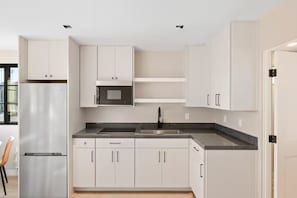 A modern kitchen with white cabinets, a stainless steel refrigerator, a microwave, and a sink. - Bay in View Steps to the Sand! Casita with it all! (San Diego)