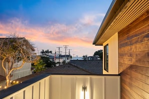A residential area with a wooden house, a white fence, and a view of the city skyline at sunset. - Bay in View Steps to the Sand! Casita with it all! (San Diego)