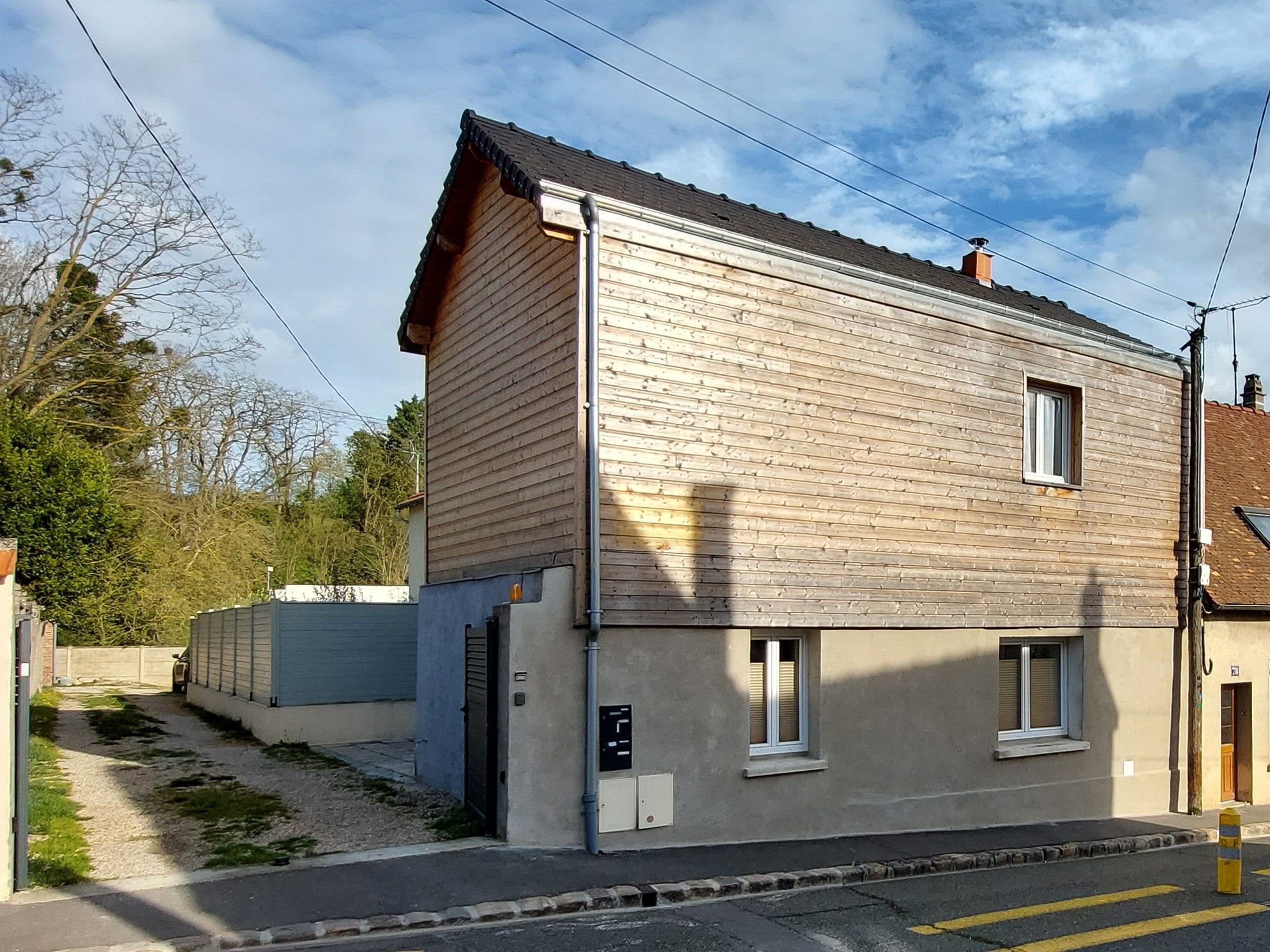 A two-story building with a sloped roof, a garage, and a small front yard.