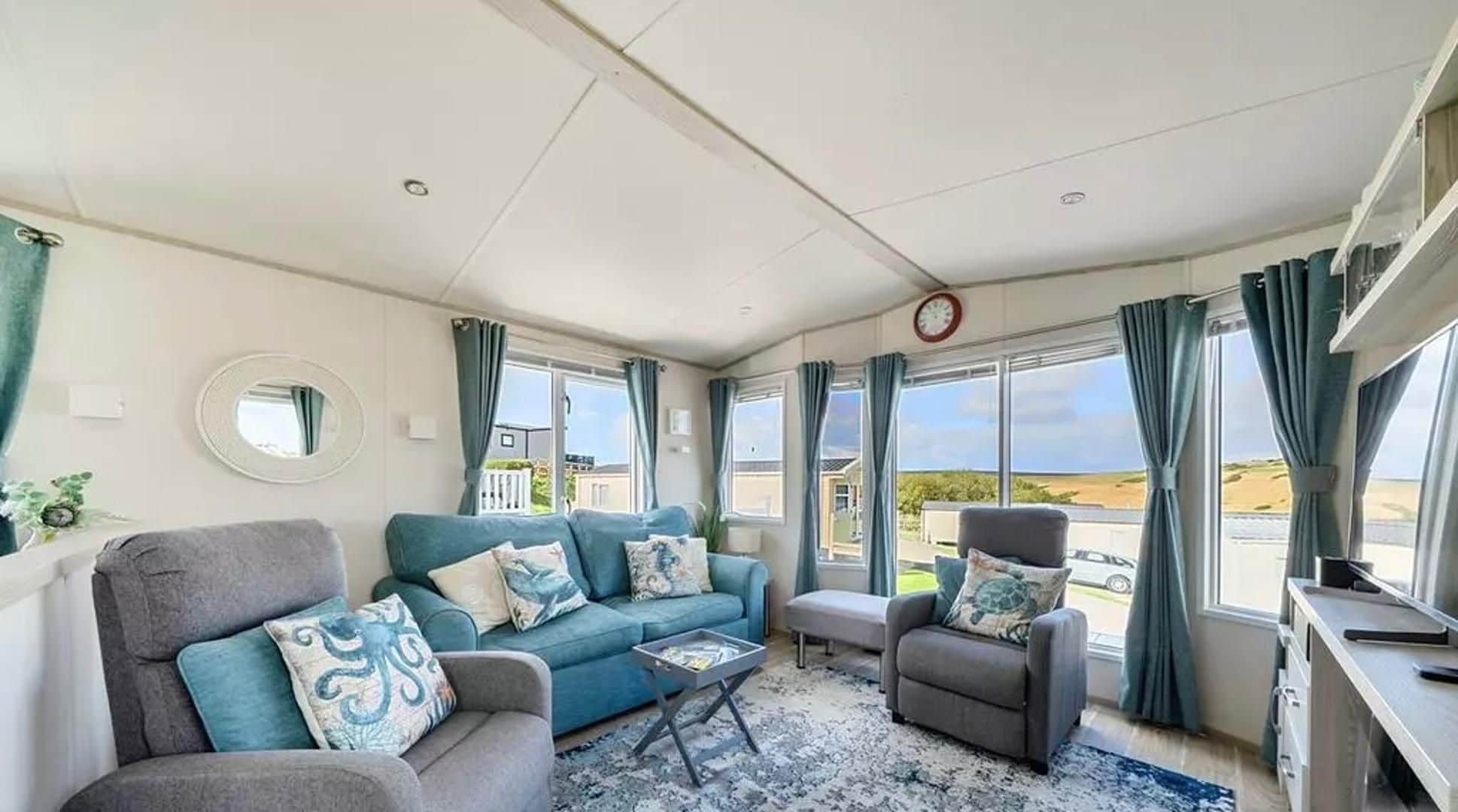 A spacious living room with a sofa, armchair, and a small table.