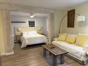 Ein Schlafzimmer mit einem Bett, Nachttischen, einer hölzernen Bank, einem Sofa und einer Lampe.