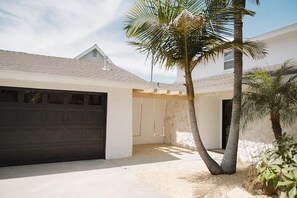 Una propietat residencial amb garatge, terrassa coberta i una palmera.