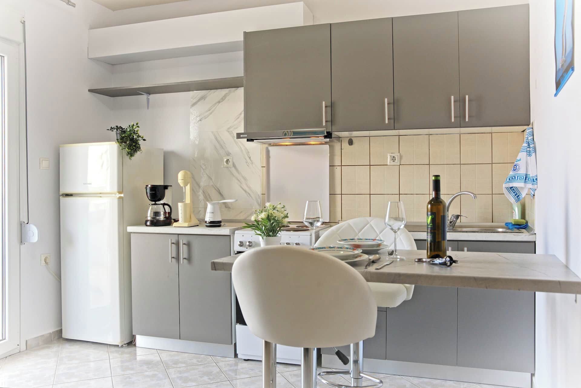 A modern kitchen with a built-in oven, a coffee maker, a kettle, and a wine bottle on the counter.