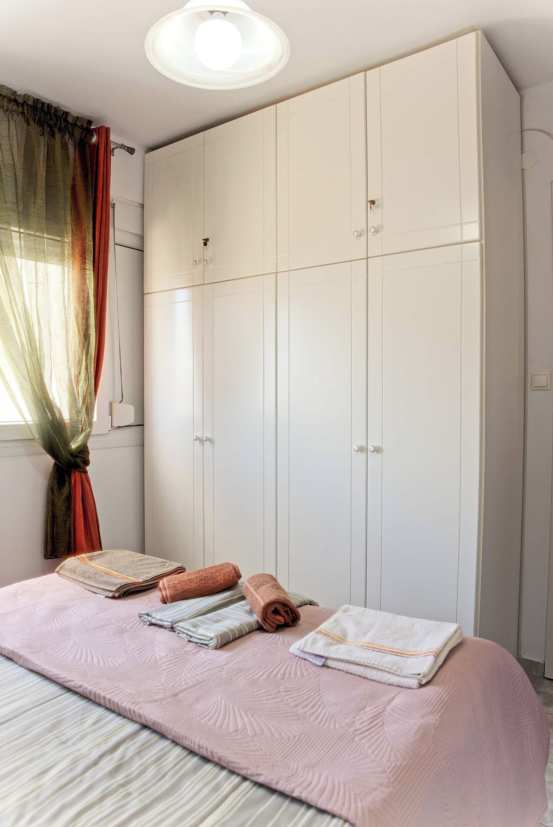 Een slaapkamer met een groot bed, een kledingkast en een raam met gordijnen.