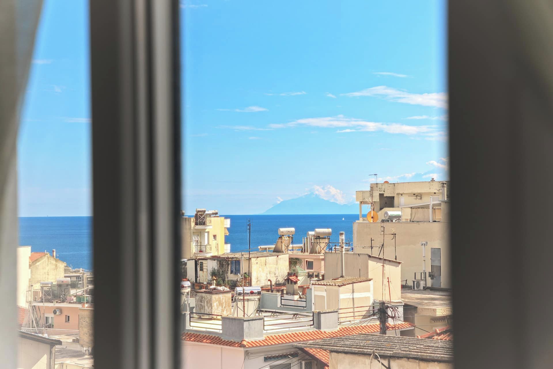 A coastal cityscape with buildings and a mountain in the distance.