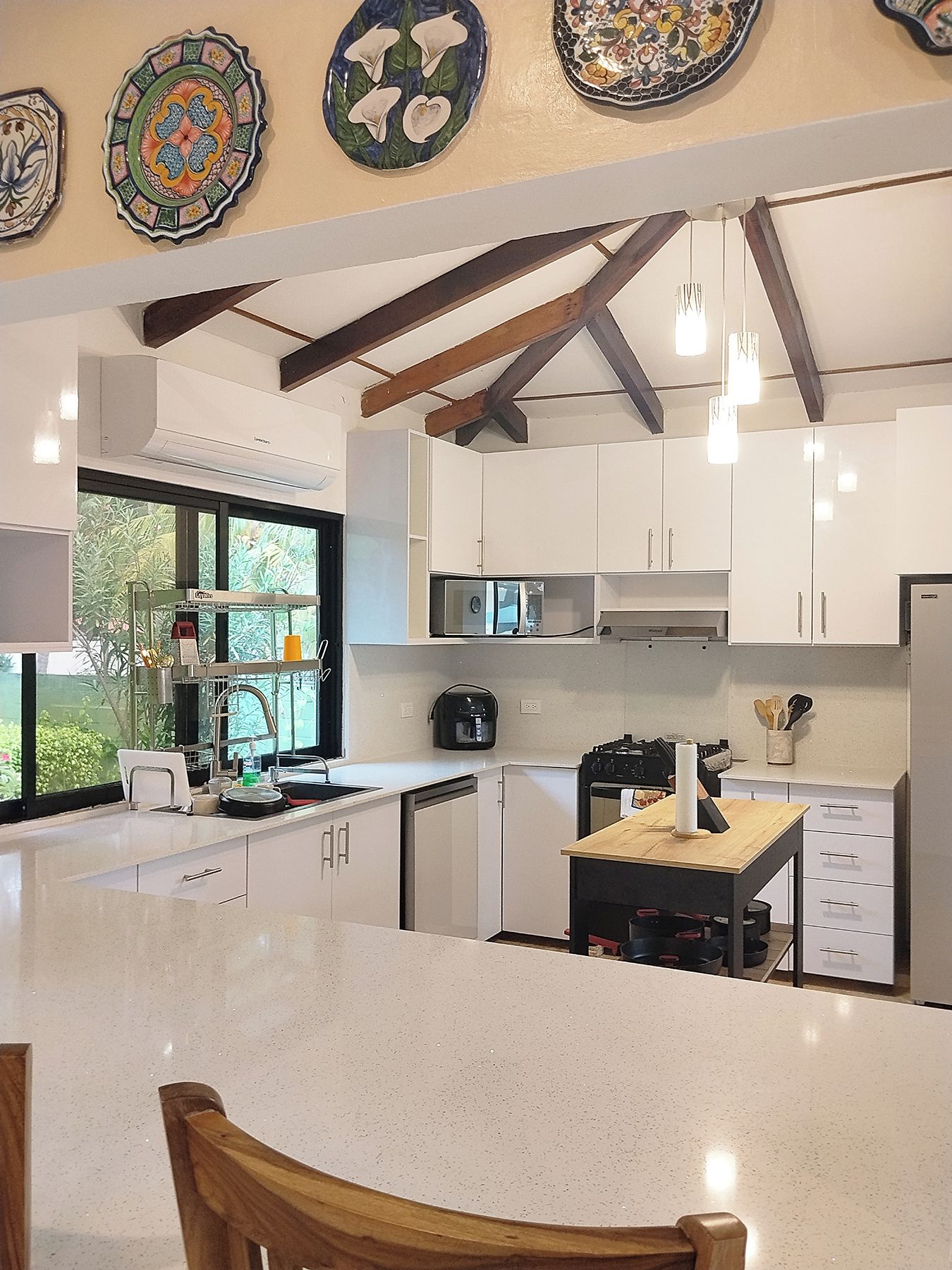 A modern kitchen with white cabinets, a central island, and a window providing natural light.