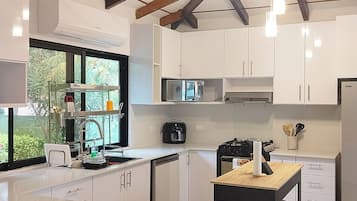 A modern kitchen with white cabinets, a central island, and a window providing natural light.