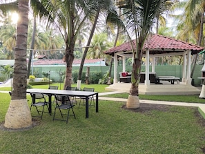 An outdoor patio area with a gazebo, a dining table with chairs, and palm trees. - New Listing (Amatecampo)