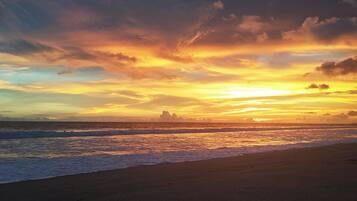 A beach with waves and a sunset.