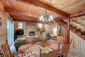 A cozy cabin interior with a wooden interior, a fireplace, a dining table with chairs, and a staircase. - Cozy 4-bedroom Cabin in Blue Lake Springs Arnold (Arnold)