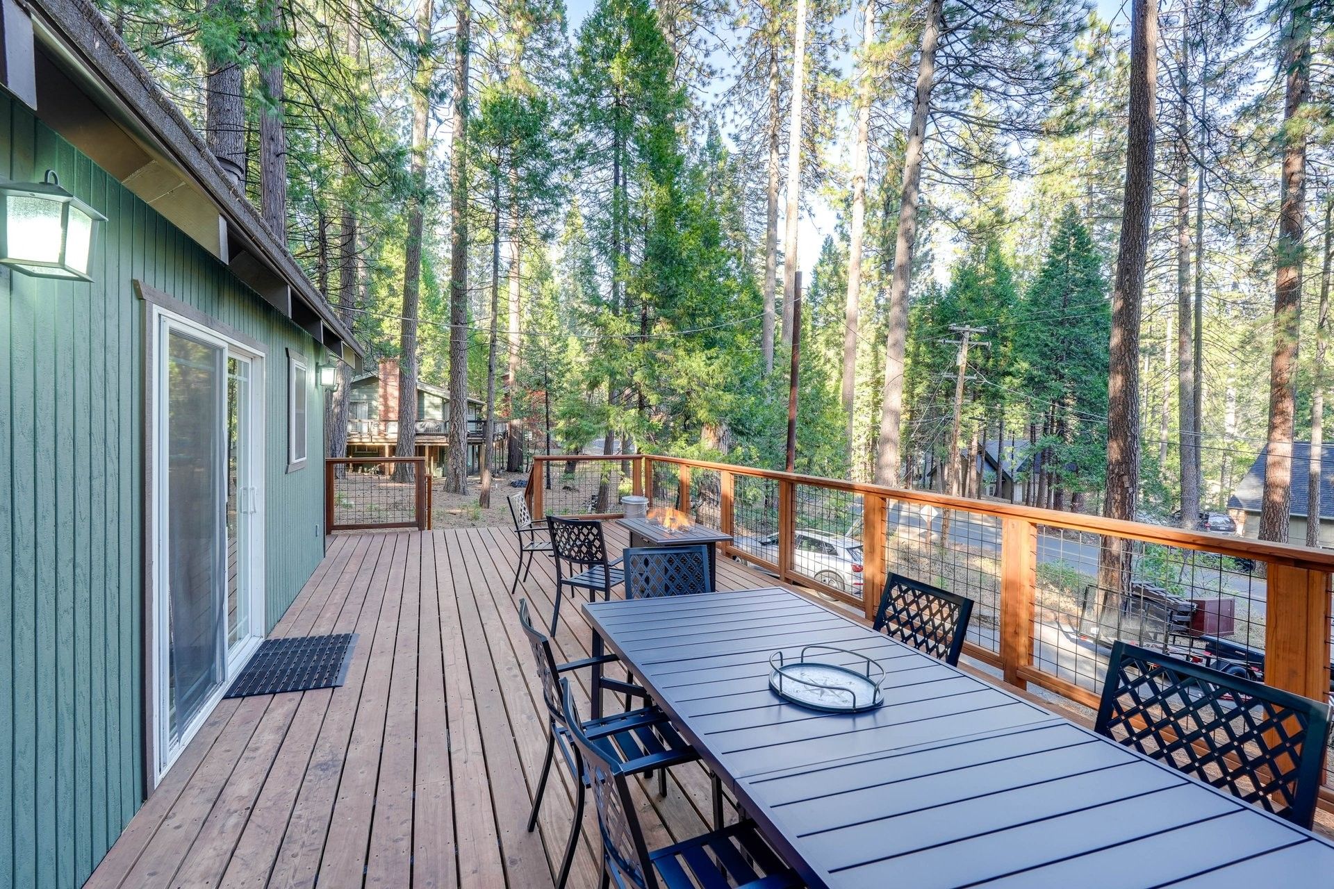 Une terrasse avec une table et des chaises, entourée de grands arbres.