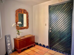 Ein Badezimmer mit einem Holzkosmetikschrank, einem Spiegel mit aufwendiger Rahmung, einer Vase mit Blumen und einem dekorativen Schild.