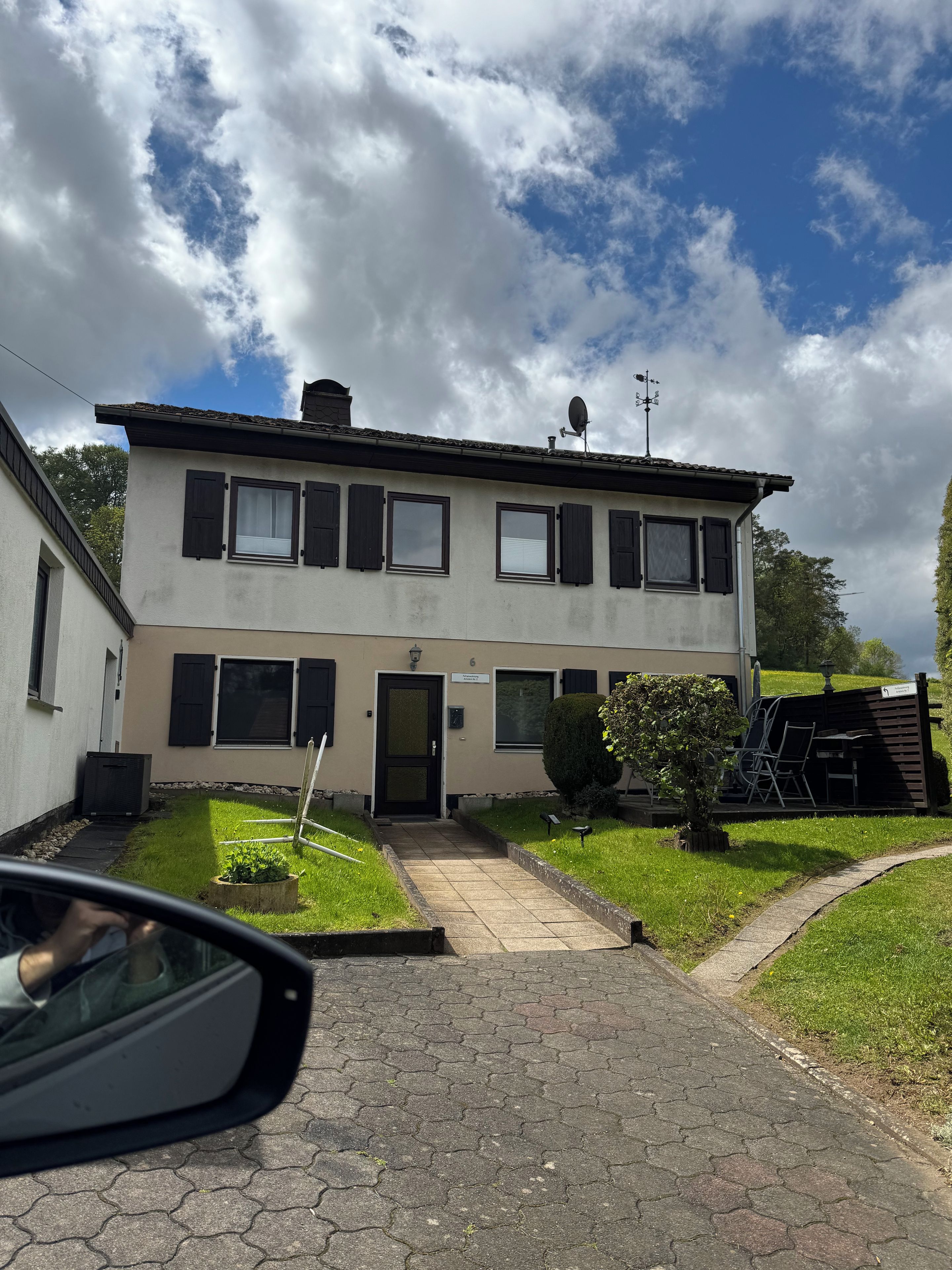 A two-story building with a flat roof, a satellite dish, and a paved driveway leading to the entrance.