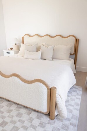 Een bed met een houten frame en witte beddengoed.