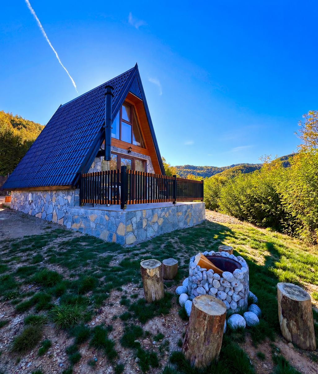 Una casa de piedra con techo inclinado y cerca de madera.