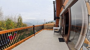 A balcony with a view of the countryside, a table with chairs, and a door leading to the interior. - House Mia – The Perfect Escape for Relaxation & Unforgettable Moments (Bijelo Polje)