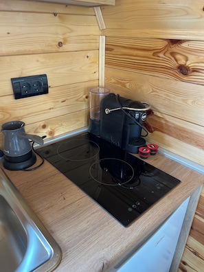 A compact kitchenette with a built-in stove, a coffee maker, and a power outlet. - House Mia – The Perfect Escape for Relaxation & Unforgettable Moments (Bijelo Polje)