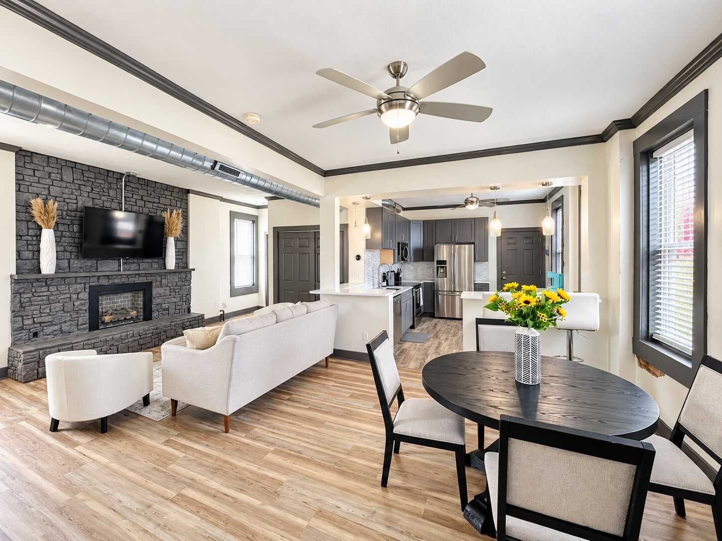 A modern interior with a living area, dining space, kitchen, and a fireplace.