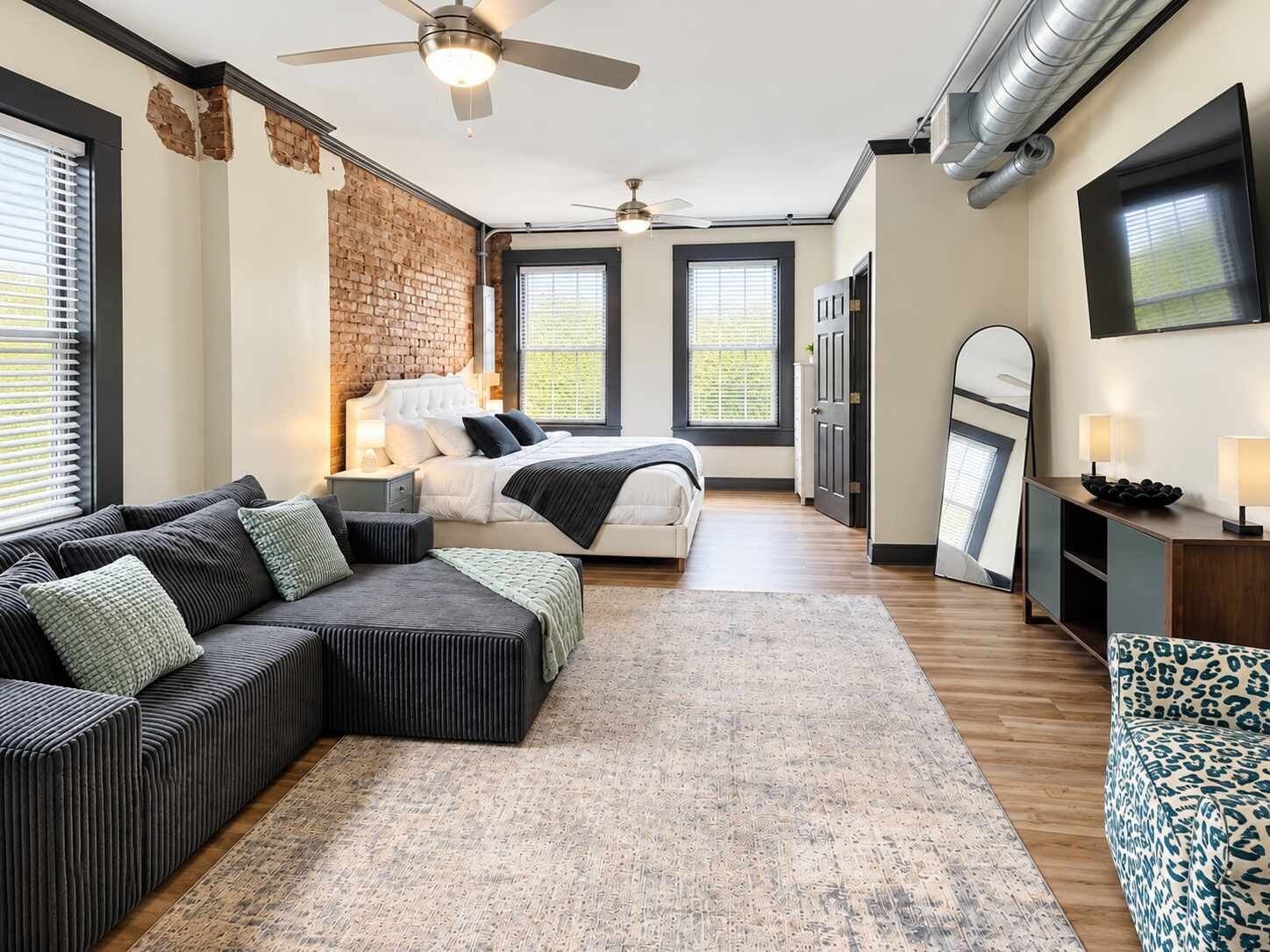A modern bedroom with a large bed, a seating area, and a television.