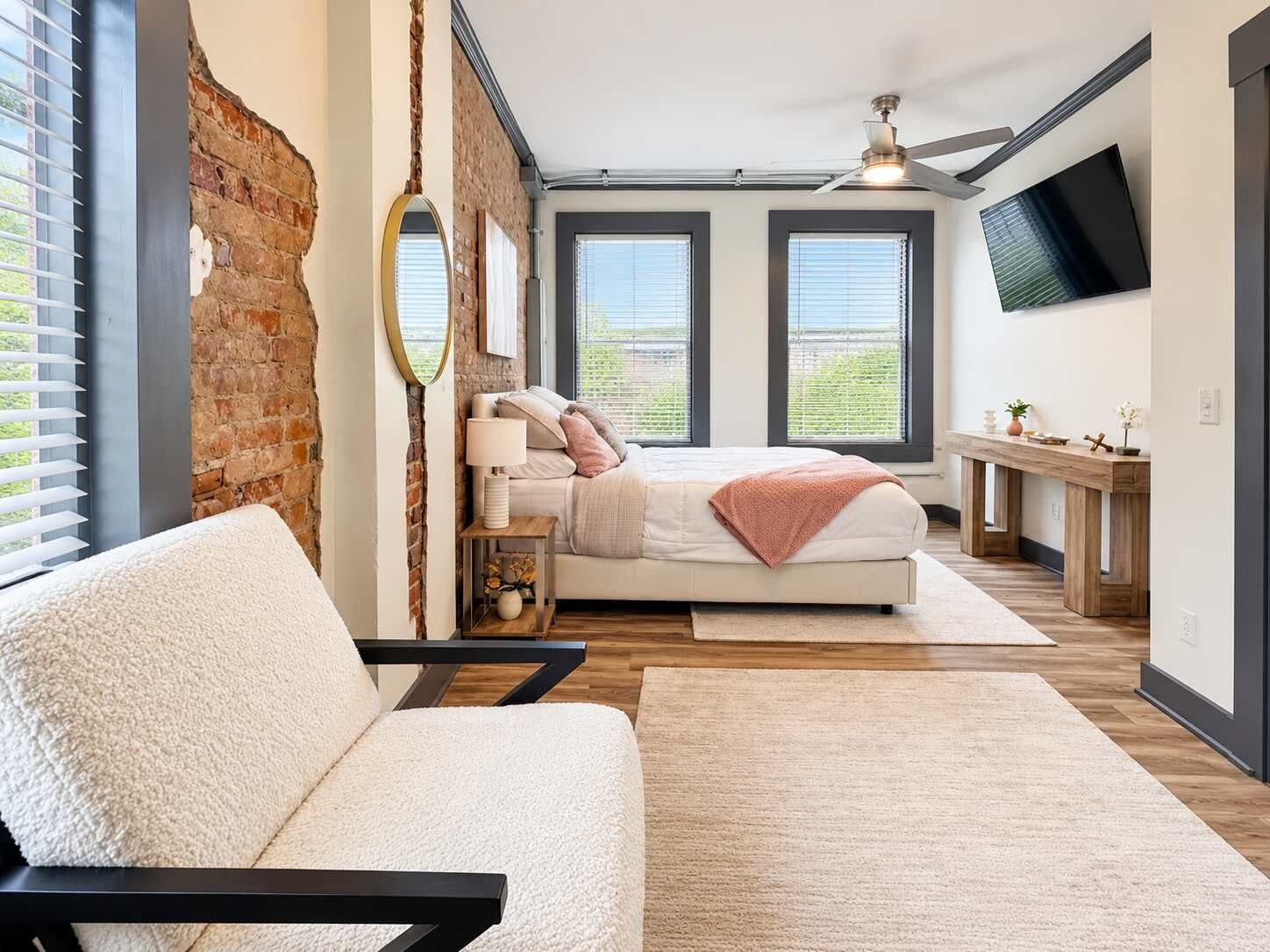 A bedroom with a bed, a sofa, a desk, and a TV.