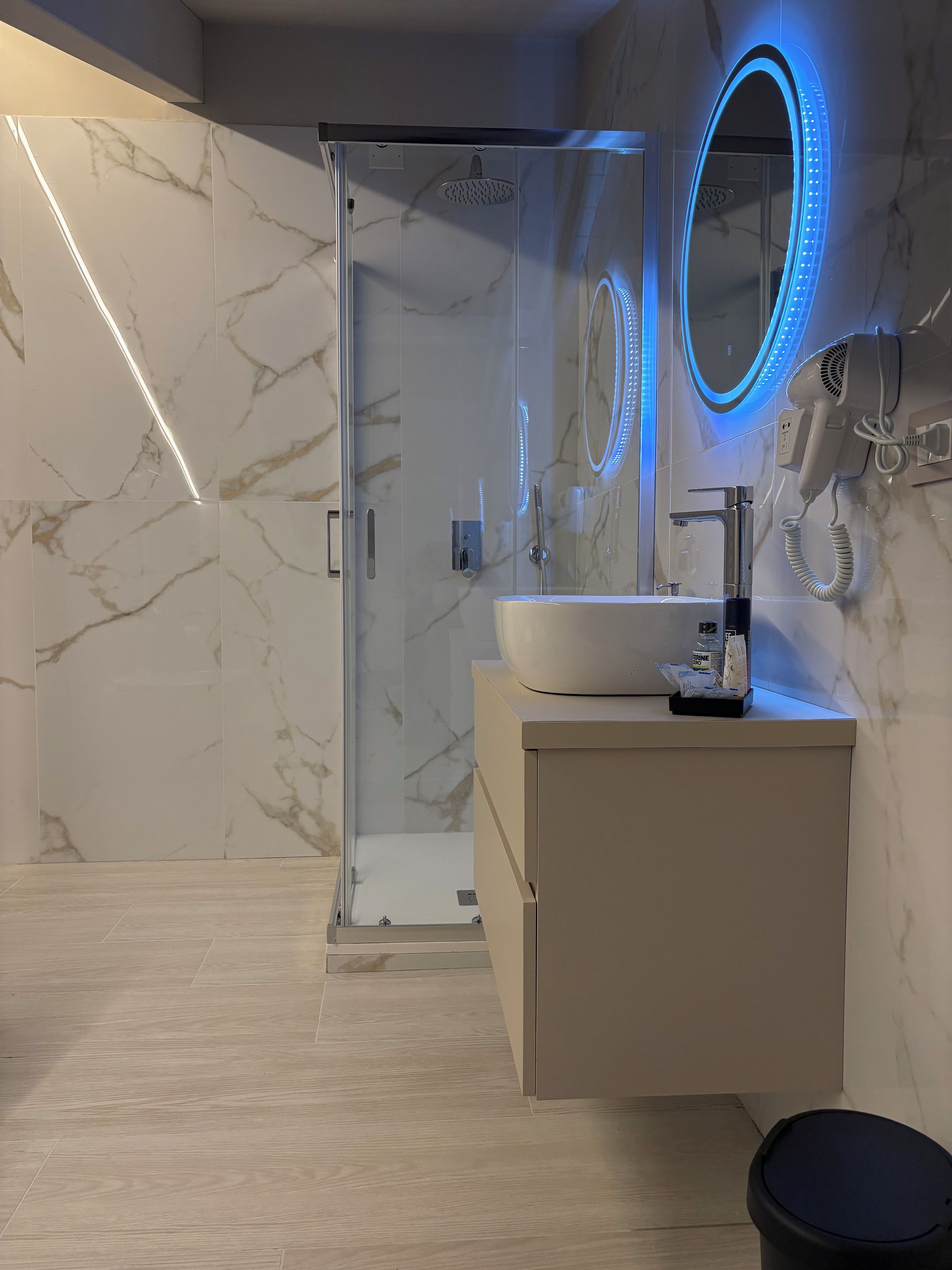 Ein modernes Badezimmer mit einer gläsernen Duschkabine, einem Waschtisch und einem Spiegel mit LED-Beleuchtung.