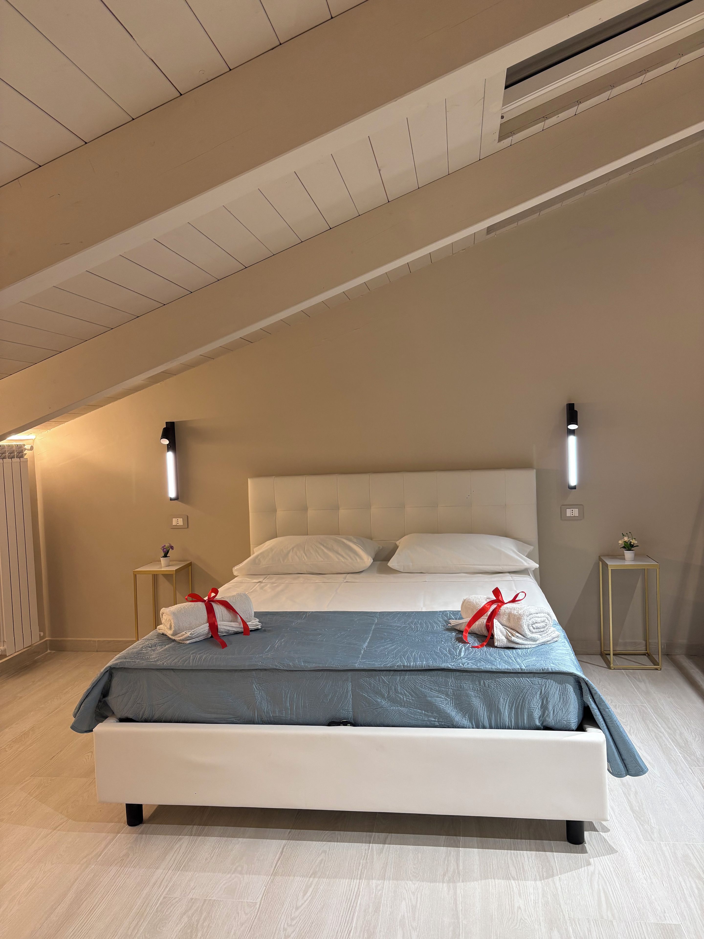 Ein Hotelzimmer mit einem Bett, zwei Nachttischen, einer Wandleuchte und einem Deckenlüfter.