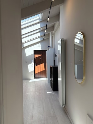A hallway with a skylight, a radiator, a mirror, and a door leading to another room. - B&B Molly (Napoli)