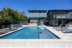 A swimming pool with lounge chairs and a staircase leading to a building. - Your Modern Lux Pool Resort in the Heart of SD (San Diego)