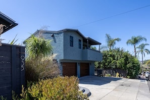 A two-story house with a garage, surrounded by greenery and palm trees. - Your Modern Lux Pool Resort in the Heart of SD (San Diego)
