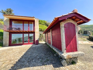 Un edificio de dos pisos con un balcón y un muro de piedra.