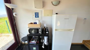 A kitchenette with a microwave, a refrigerator, a wooden box, and a first aid kit.