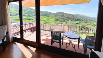 Una habitación con un gran ventanal corredero que da a una terraza exterior con mesa y sillas.