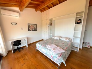 Un dormitorio con cama, escritorio y armario.