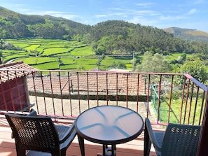 Un balcó amb taula i cadires amb vista a camps terrassats.