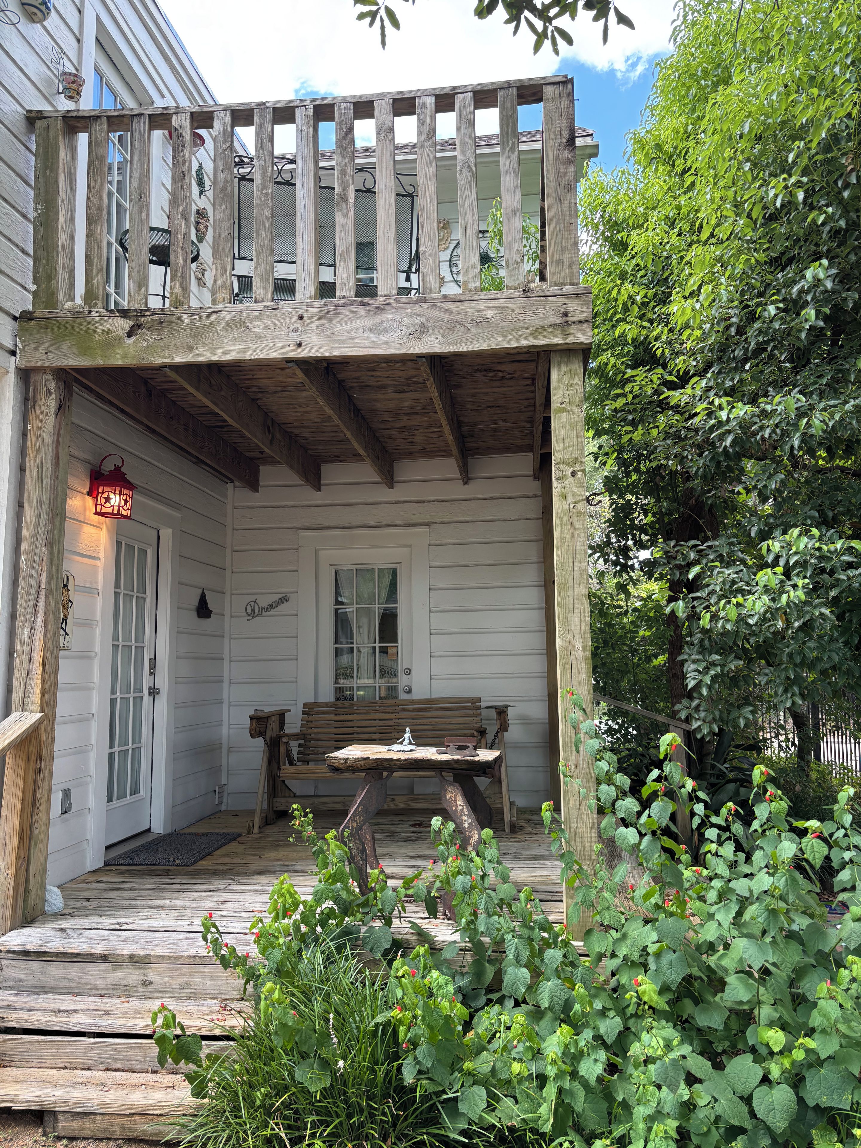 A wooden porch with a bench, a door, and a railing.