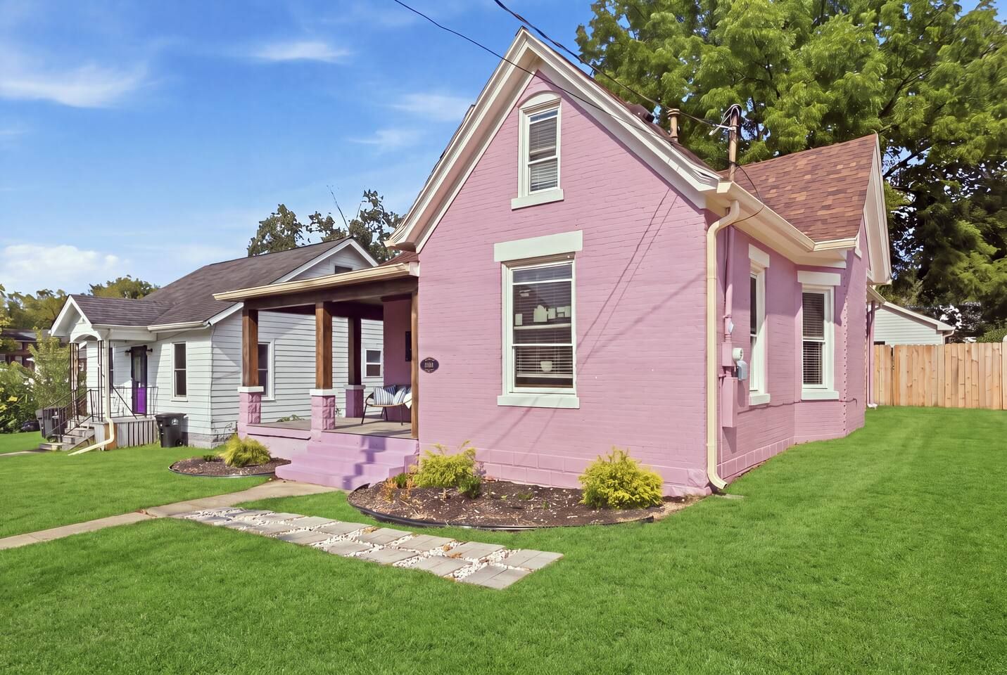 A two-story house with a pink exterior, a front porch, and a well-maintained lawn.