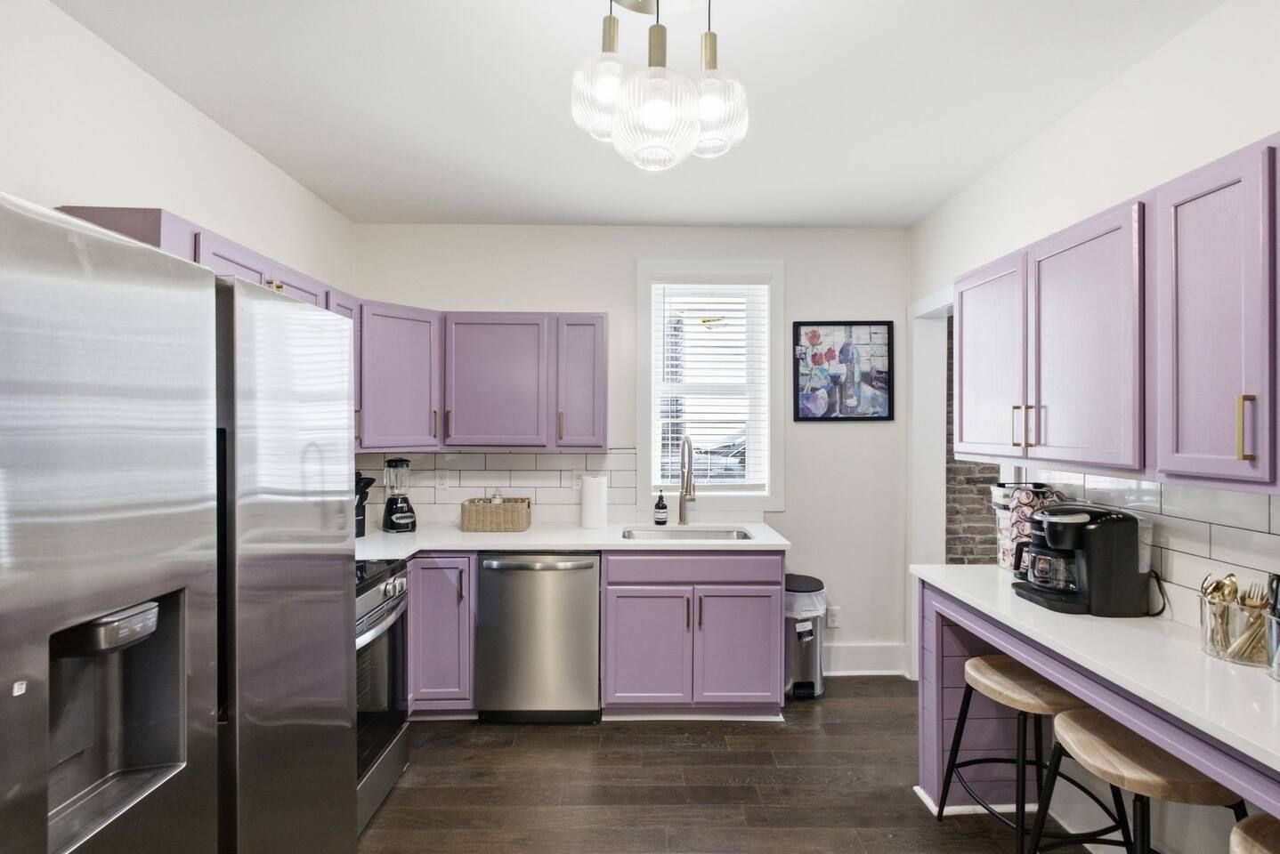 A modern kitchen with purple cabinets, stainless steel appliances, and a bar area with stools.